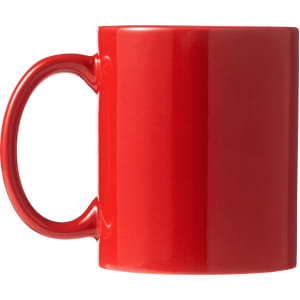 A red ceramic coffee mug with a handle, presented in a folded box.