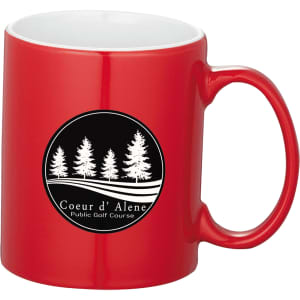 A red ceramic mug with a black logo featuring trees and a white interior, presented in a folded box.