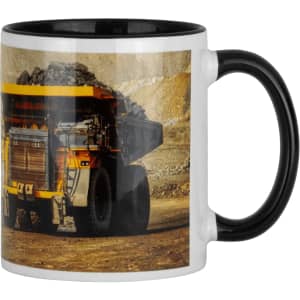 A ceramic mug with a black handle features a large yellow and black mining truck design.