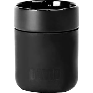 A ceramic tumbler in black with a silicone wrap, featuring a logo on the surface.