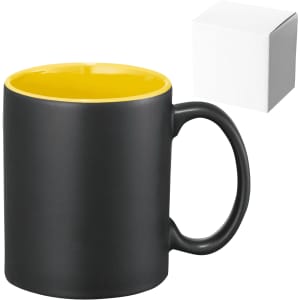 A ceramic coffee mug with a matte black exterior and yellow interior, accompanied by a plain white box.