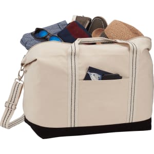 A cream and black cotton canvas duffel bag filled with assorted clothing items and accessories. It has a logo.