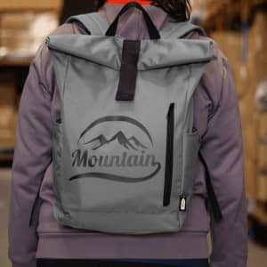 A grey roll-top backpack with a logo, featuring two side pockets and adjustable straps.