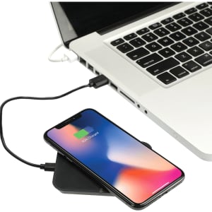 A wireless charging phone stand in black connected to a laptop, with a phone on the stand displaying a charging notification.