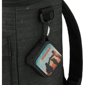 A black waterproof Bluetooth speaker with colourful designs, attached to a bag with a clip.