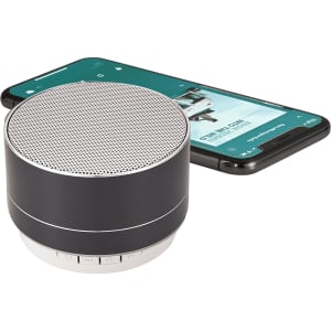 A black aluminium Bluetooth speaker next to a smartphone, showcasing its compact design and modern features.