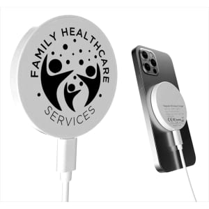 A white magnetic wireless charger with a logo, positioned next to a smartphone.