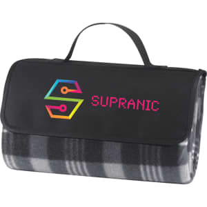 A folded picnic rug in grey and black checkered pattern with a black carrying strap and a logo on the front.