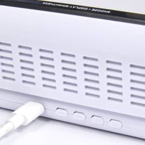 A white digital power clock with buttons and a charging port, featuring a sleek design and a logo.