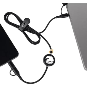 A black charging cable with a circular connector, linking a device to a laptop, featuring a logo.