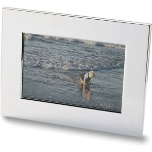 A nickel plated photo frame showcasing a beach scene with a child playing by the water.