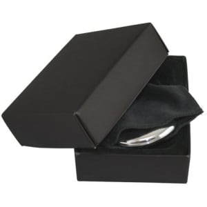 A silver compact mirror inside a black box, resting on a soft black cloth. The box has a minimalist design.