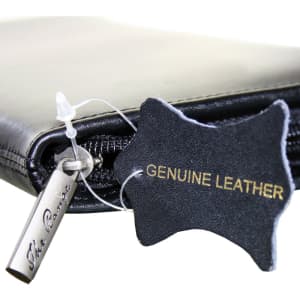 A black leather travel wallet featuring a zipper and a tag indicating genuine leather. It has a small branding logo.