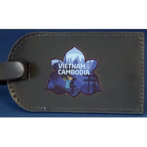 A dark luggage tag featuring a floral design and an illustration representing Vietnam and Cambodia.