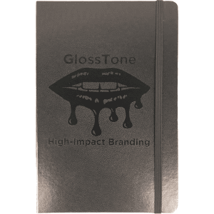 A black journal with an elastic band and a logo on the cover, featuring a glossy finish.