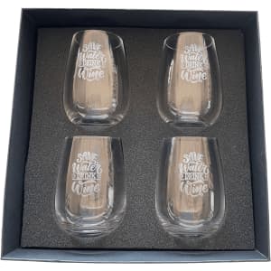 A set of four clear glass wine glasses with etched white text, presented in a black gift box.