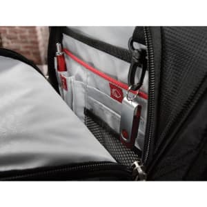 A black backpack interior featuring compartments with red accents and a USB flash drive attached.