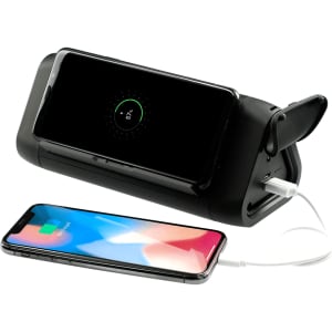 A black power bank and speaker with a smartphone charging on one side and another smartphone placed nearby.