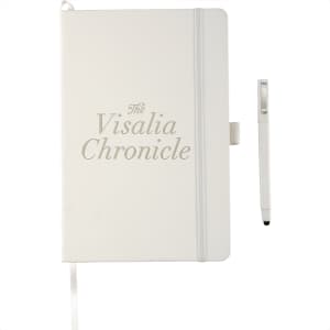 A white hardbound journal with a pen, featuring a logo and a ribbon bookmark.