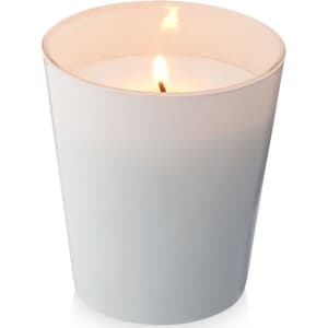 A white scented candle in a glass container, featuring a lit wick, with a soft glow.