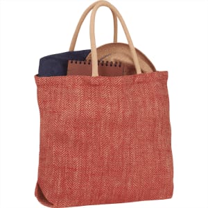 A herringbone-patterned jute tote bag in red and natural colours, featuring two handles and items inside.