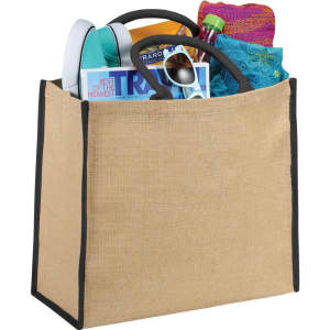 A large jute tote in natural colour with black trim, filled with a magazine, drink bottle, flip-flops, and a towel.