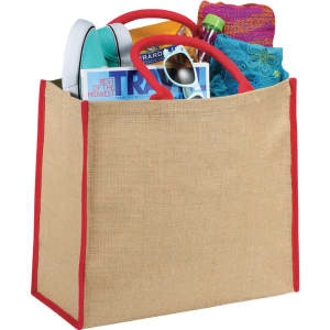 A large jute tote bag in natural with red trim, filled with various items including magazines, a drink bottle, and accessories.