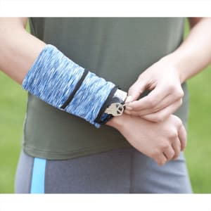 A person wearing a blue heathered wristband with a pocket, adjusting it on their wrist.
