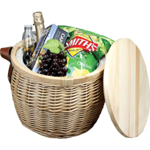A wicker cooler basket in natural tones, containing drinks, snacks, and a wooden lid. It features a logo.