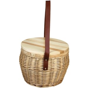 A wicker cooler basket in natural tones with a wooden lid and a brown leather strap. Contains no visible items.