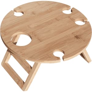 A round bamboo picnic table with cutouts for drink bottles and collapsible legs. It has a natural finish.