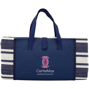 A navy picnic rug with a striped design, featuring sturdy handles and a logo on the front.