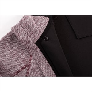 A close-up of a maroon and black zip hoodie featuring a textured fabric and an inner lining. It has a logo.