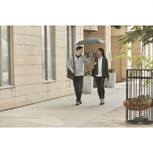 A man and a woman walk together under an umbrella, wearing a grey quarter zip sweater and stylish outfits.