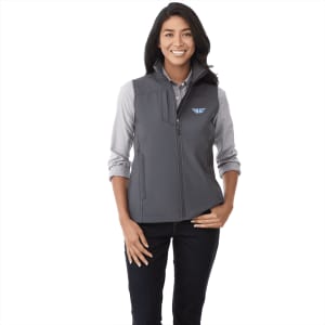 A woman wearing a grey softshell vest, featuring a logo, with a button-up shirt underneath.