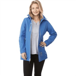 A woman in a blue rain jacket with a hood, paired with a grey top and black trousers, smiling at the camera.