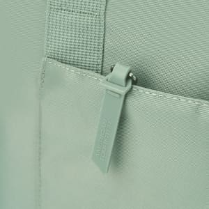 A mint green tote bag featuring a zippered pocket and textured fabric, with a logo on the zipper tag.