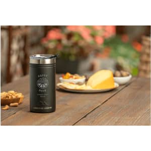 A drink bottle in black with a stainless steel top, placed on a table next to a platter of snacks.