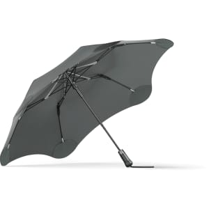 A grey BLUNT Metro Umbrella with a sleek design and a sturdy frame. It features a branding logo.