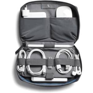 A grey tech kit featuring compartments for a charger, cables, and an airpod case, with a blue interior and a logo.