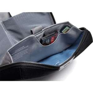 A black tech kit featuring a zippered compartment, blue lining, and pockets for organising small items and cards.