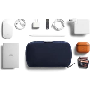 A navy tech kit contains a mouse, chargers, cables, a power bank, and an assortment of memory cards.