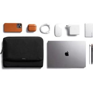 A black laptop caddy with a silver laptop, accessories in orange and white including a phone, mouse, and charger.