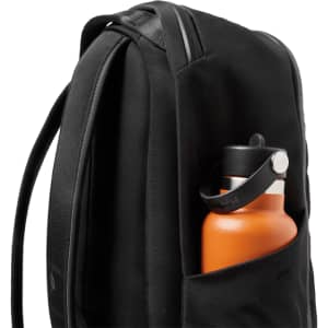 A black backpack featuring a side pocket containing an orange drink bottle. The backpack has a sleek design.