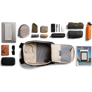 A black Bellroy Transit Workpack 20L with various contents including a laptop, pouches, clothing, and a drink bottle.