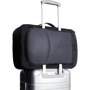 A black Bellroy Lite Travel Pack 30L backpack resting on a silver suitcase, featuring a textured panel and a logo.