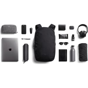 A black Bellroy Via Backpack 20L surrounded by a laptop, drink bottle, sunglasses, and various accessories.