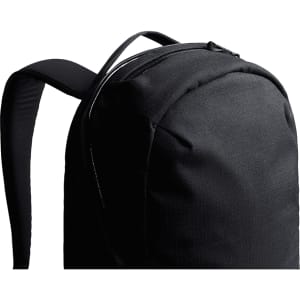 A black backpack with smooth fabric and padded straps, featuring a zippered compartment at the top.