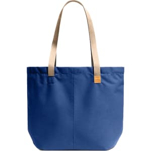 A blue tote bag with beige straps and a small logo. The bag features a simple, structured design.