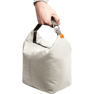 A hand holds a light grey cooler bag with a sturdy handle and a clip attachment.